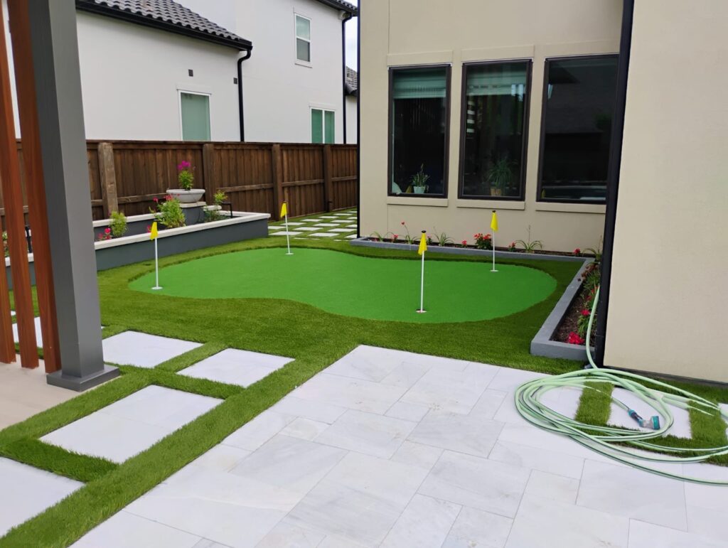 a small golf course with flags in the back and pavers with artificial turf